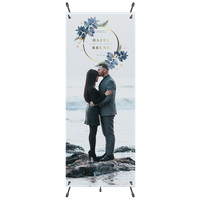 A couple embraces on a rock, surrounded by water; above them is a wreath with the text 'Save Our Date April TwentyThree.'